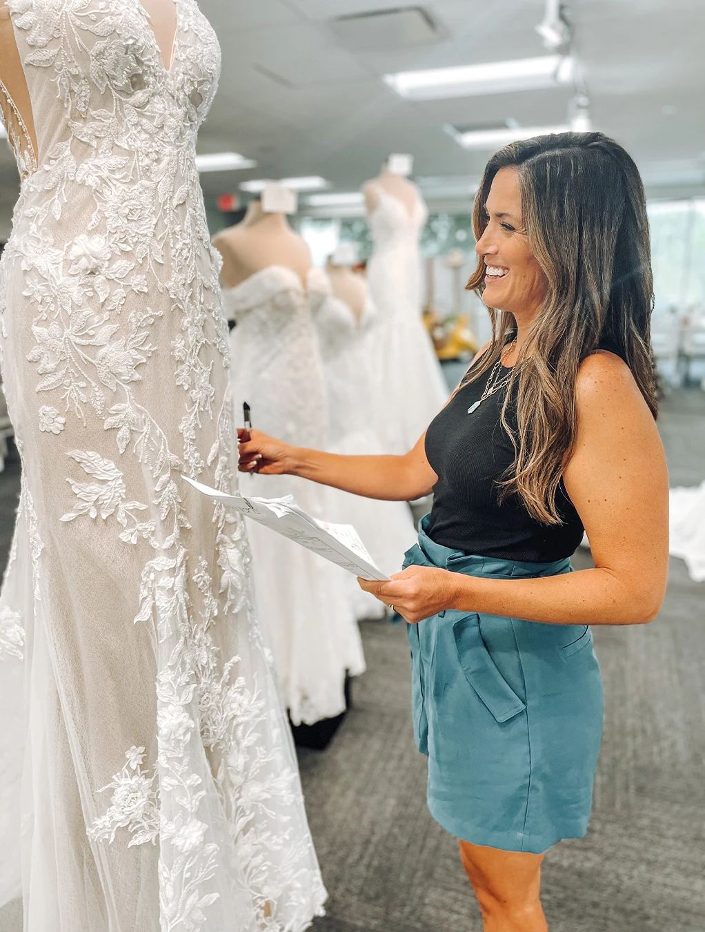 True Society Peoria owner smiling at a lace mermaid wedding dress 