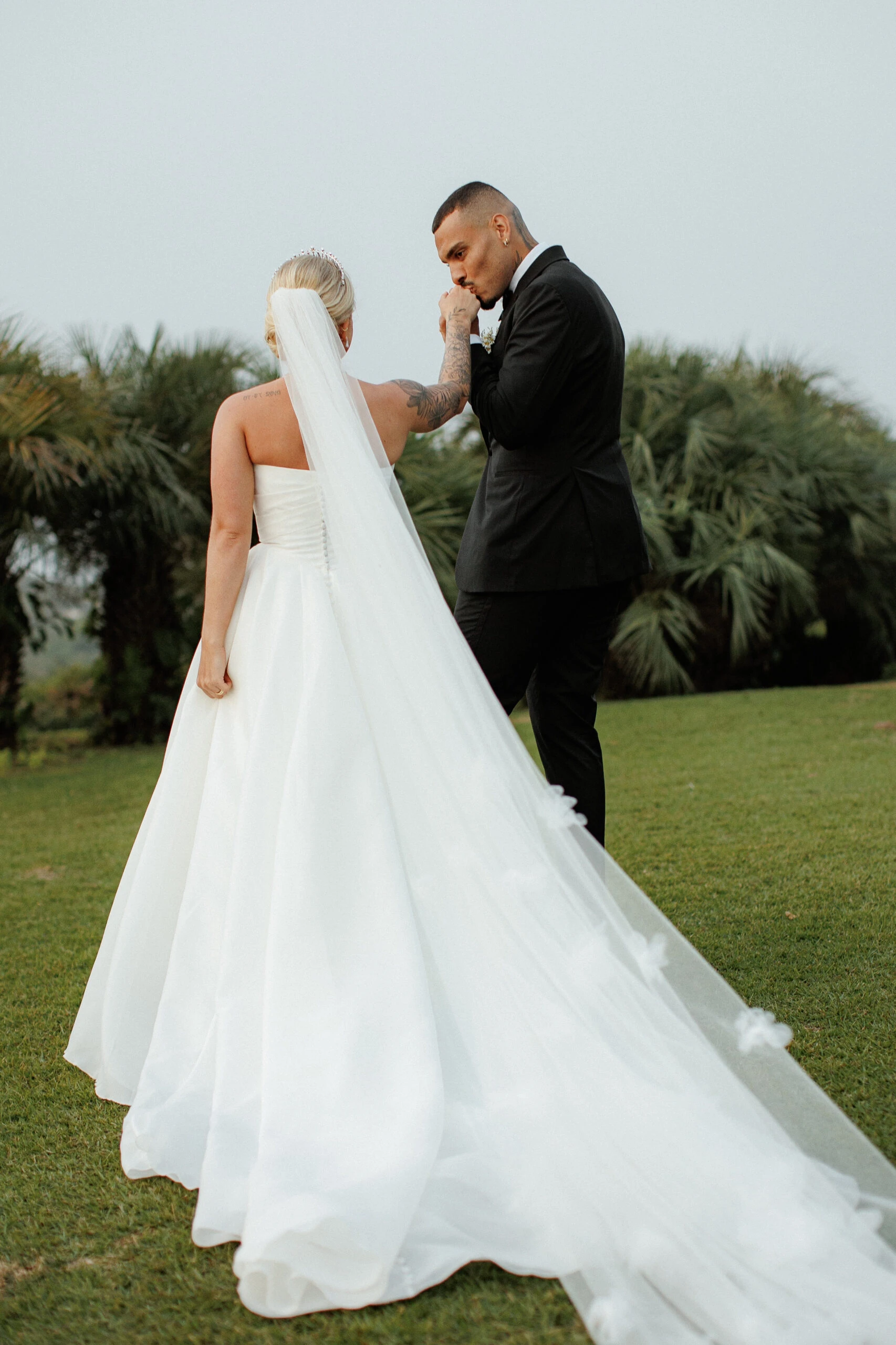 true bride Mayke wearing D3941 by Essense of Australia while husband kisses her hand