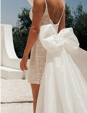 Bride wearing a mini beaded wedding dress with a large bow attached