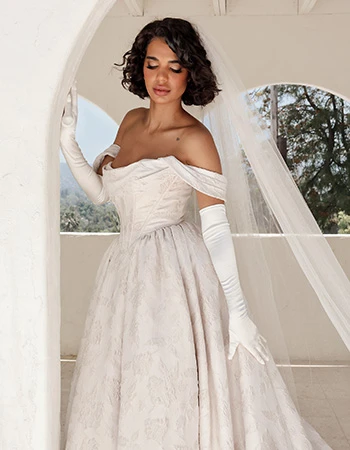 Bride wearing a textured off-the-shoulder floral ballgown wedding dress and long white sleeves