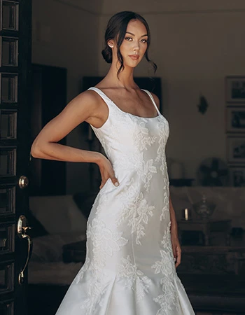 Bride wearing a textured lace wedding dress standing in a doorway.