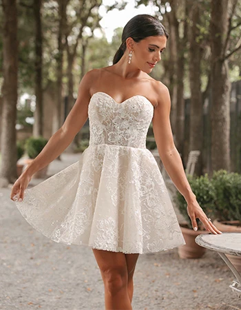 Bride wearing a mini lace sparkly wedding dress in a park