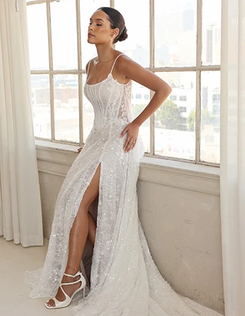 Bride wearing a sparkly wedding dress sitting on a windowsill