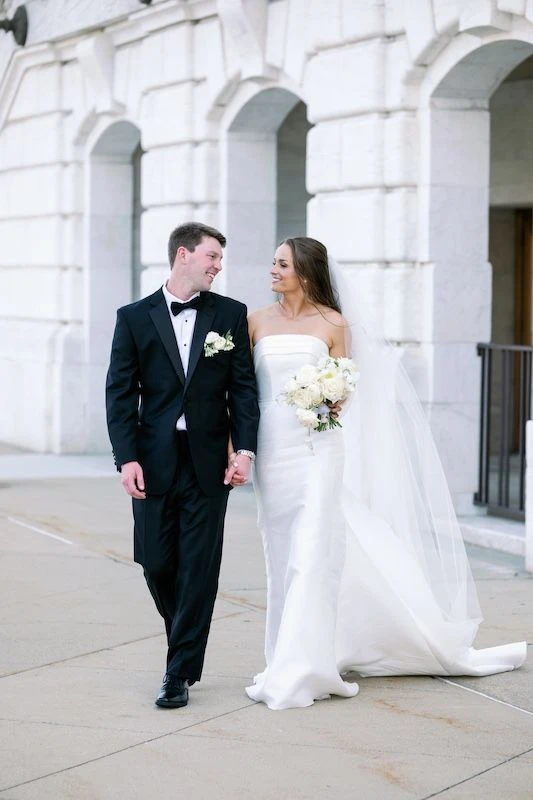 Bride and groom holding hands walking in front of a building