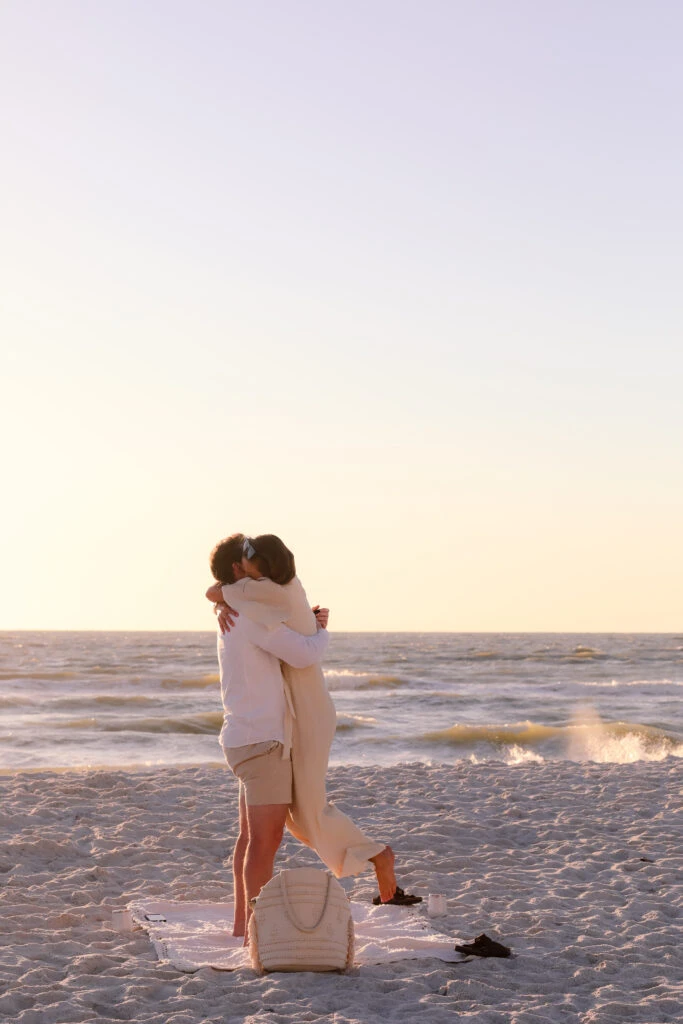 Man and Woman embracing on a beach with the ocean in the back.