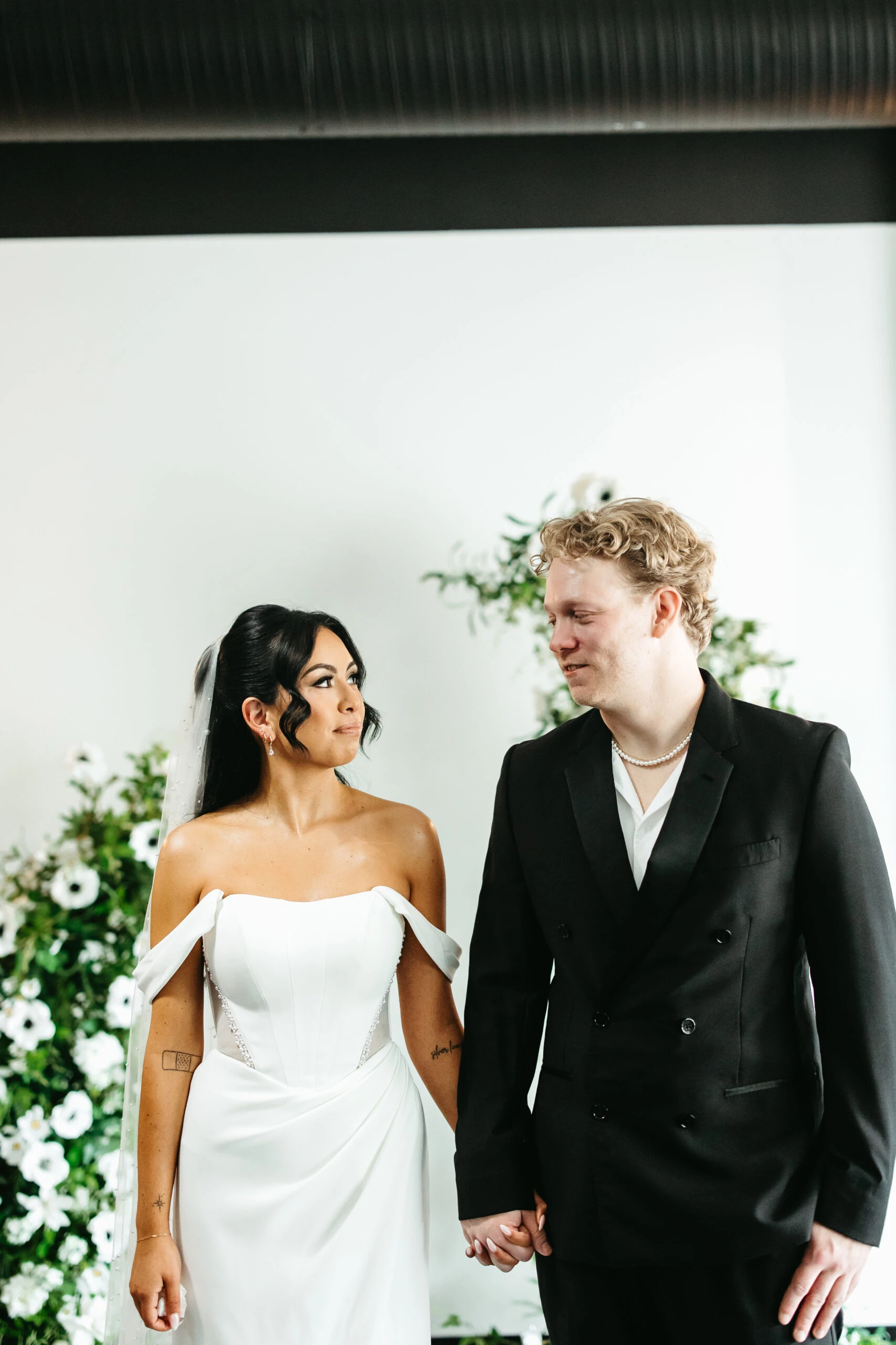 Bride and groom holding hands, looking at eachother