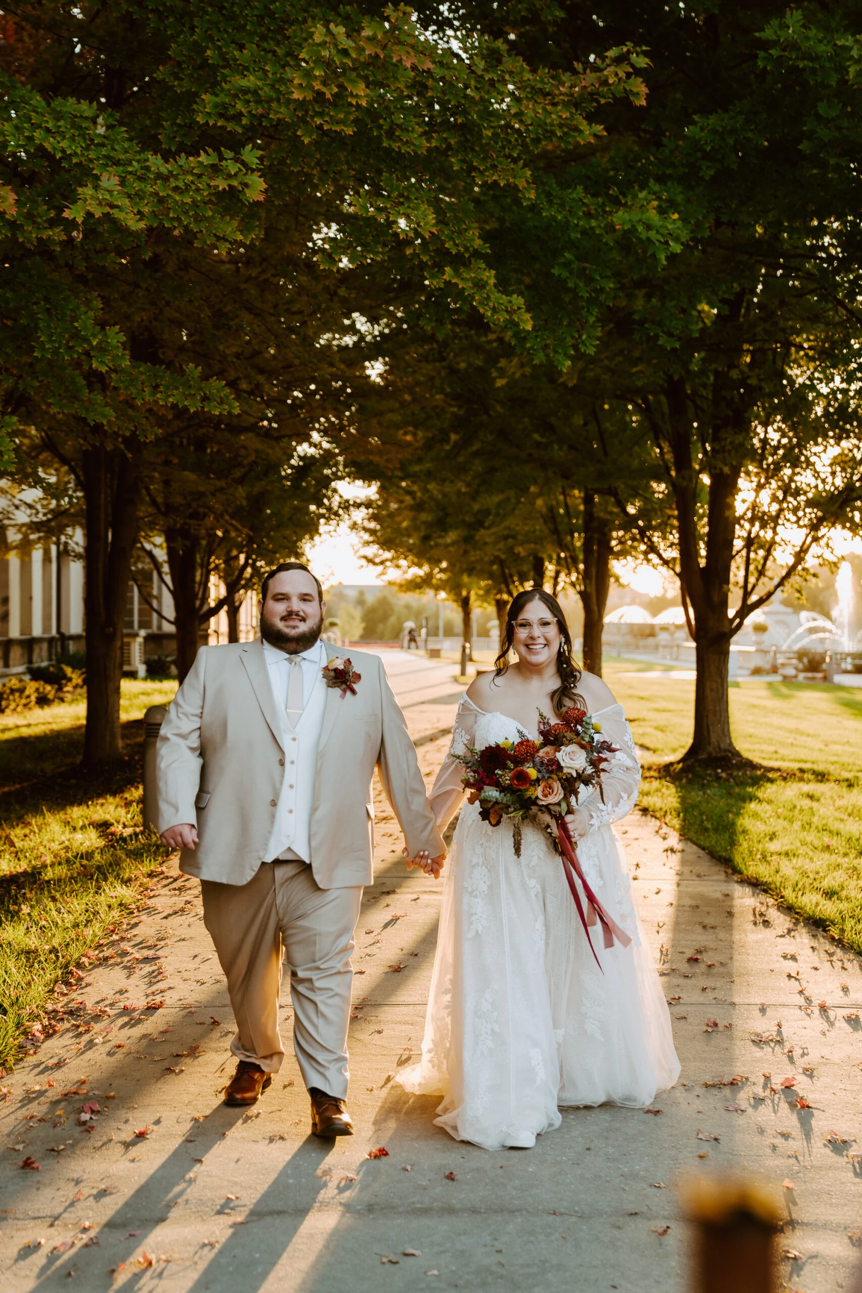 true bride Rachel holding hands with husband Thomas while walking underneath trees