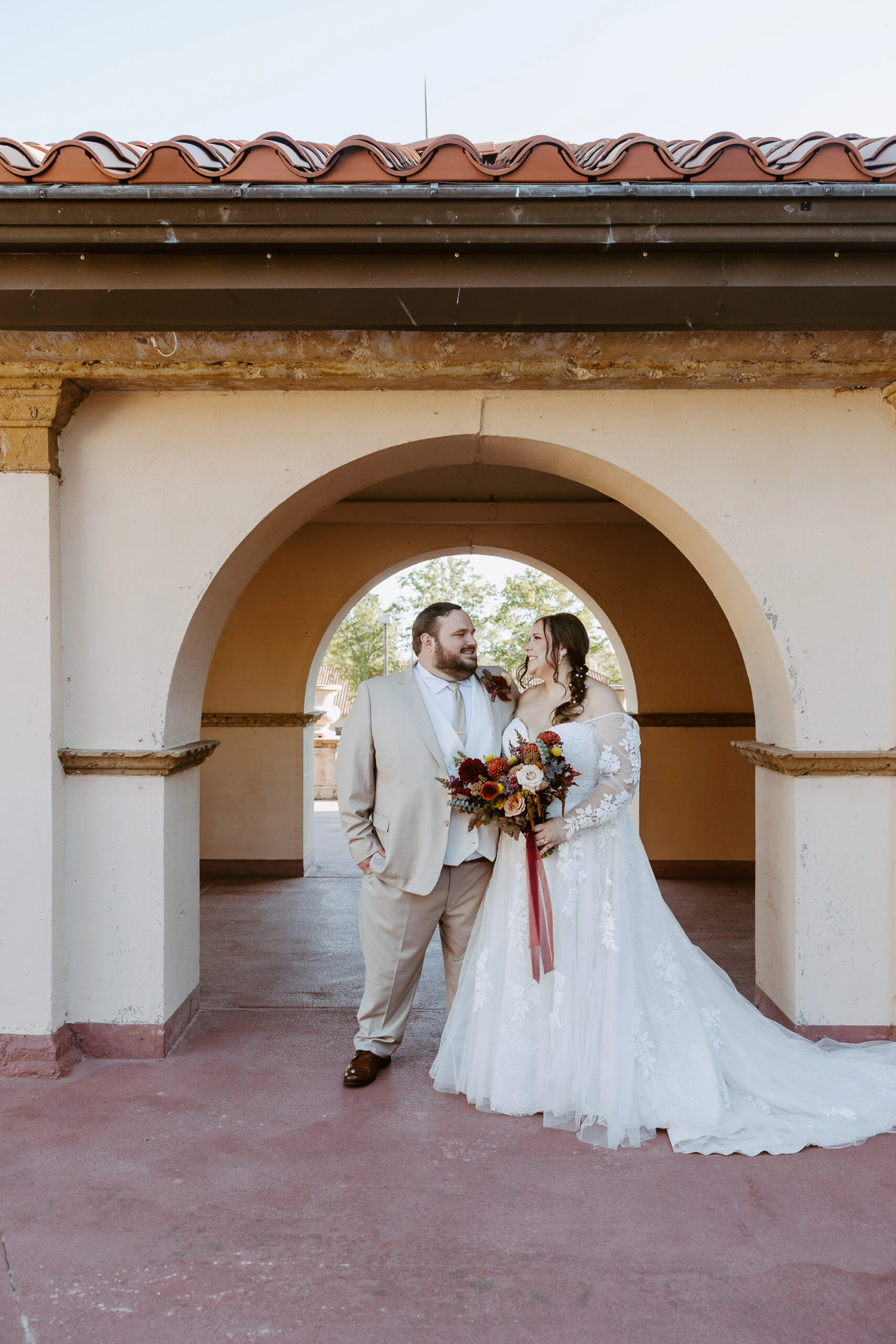 True bride Rachel posing with husband Thomas beneath archway