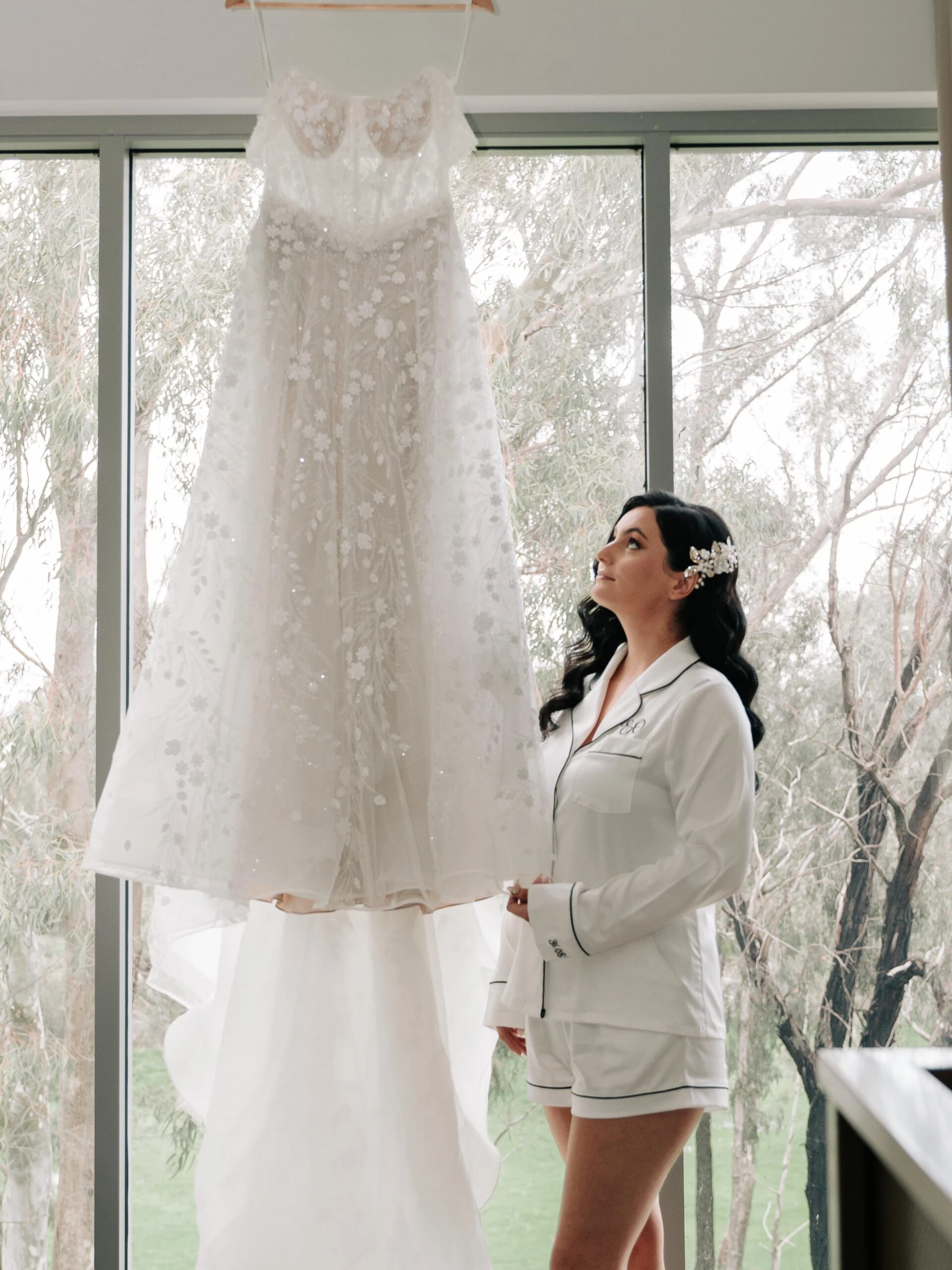 Bride looking up at her wedding dress hanging up