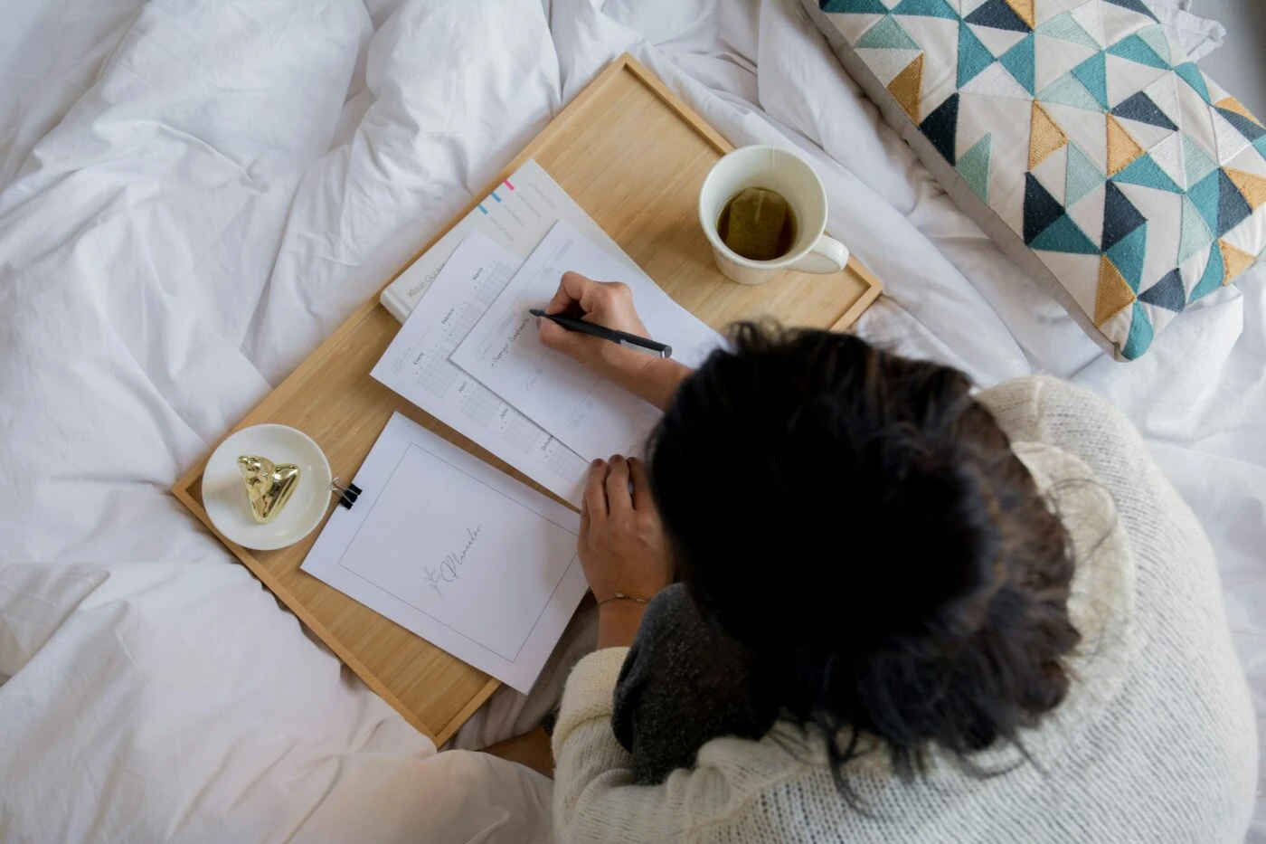 woman sitting on bed taking notes while planning wedding