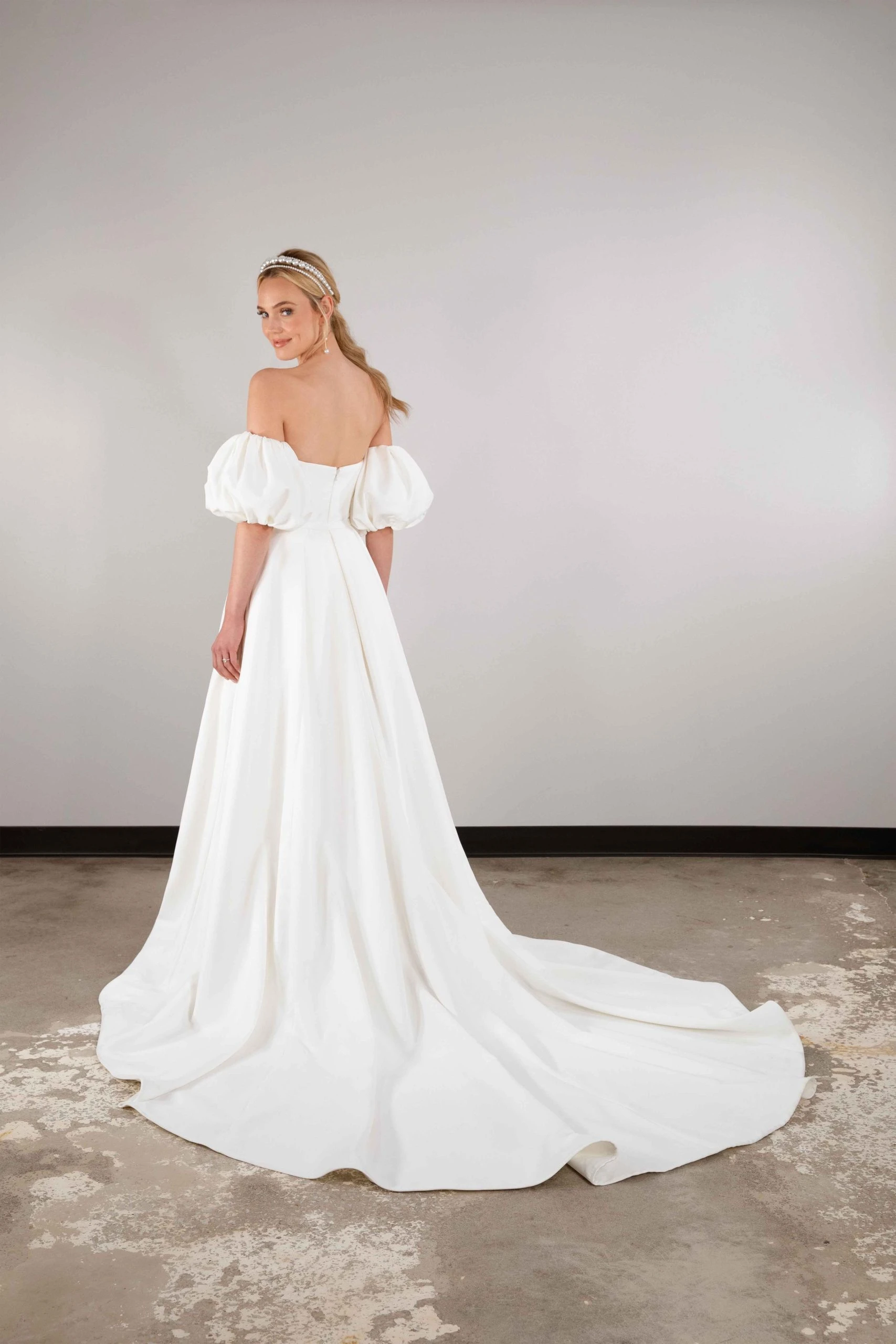 model showing of the back and skirt of simple wedding dress with off the shoulder puff sleeves and pockets - D3957 by Essense of Australia