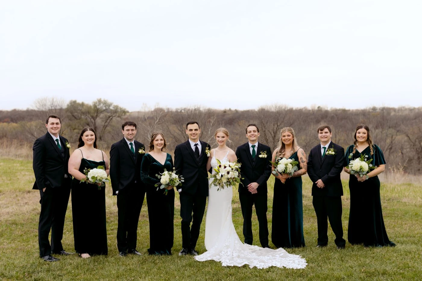 Bridal party standing in a row around groom and bride