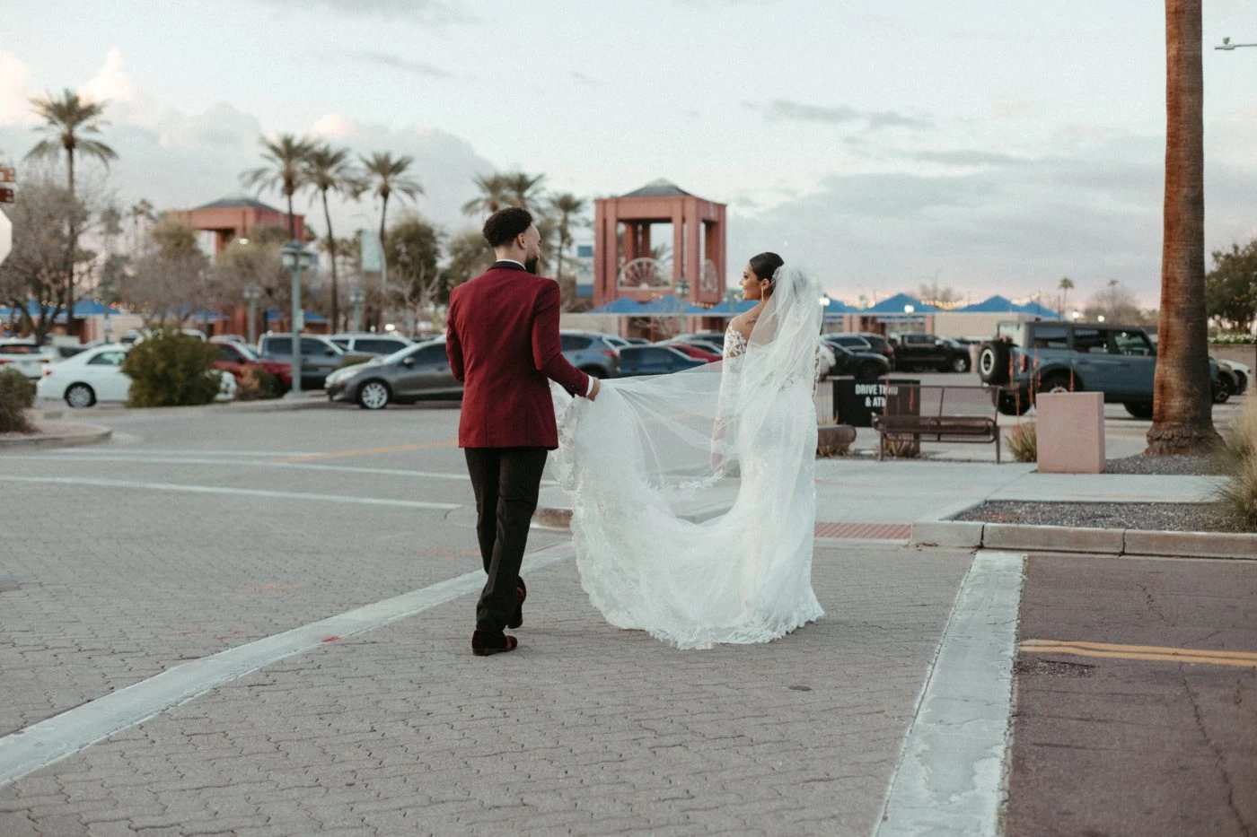 Bride and Groom walking on the street while groom is holding the train of the brides dress