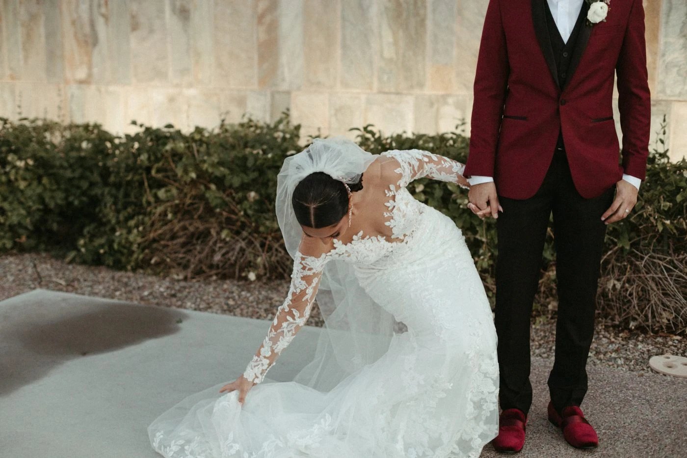 Bride and groom holding hands. Bride is fixing the bottom of the dress.