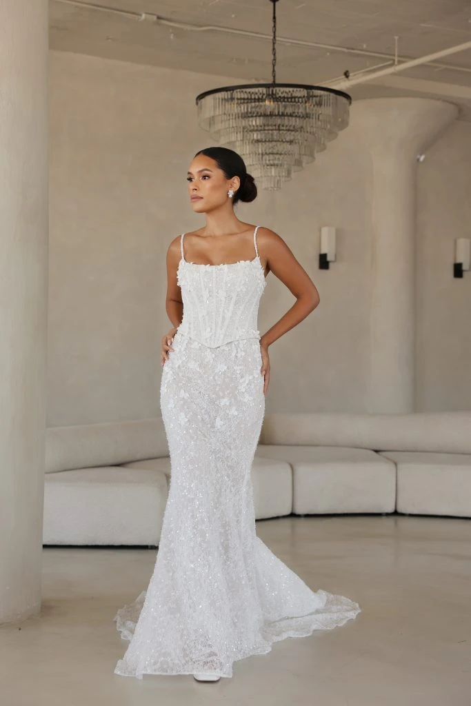 Bride standing a room wearing a spaghetti strap lace wedding dress