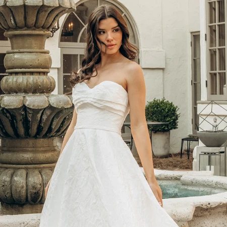 bride posing in front of a stone fountain in a strapless a-line wedding dress