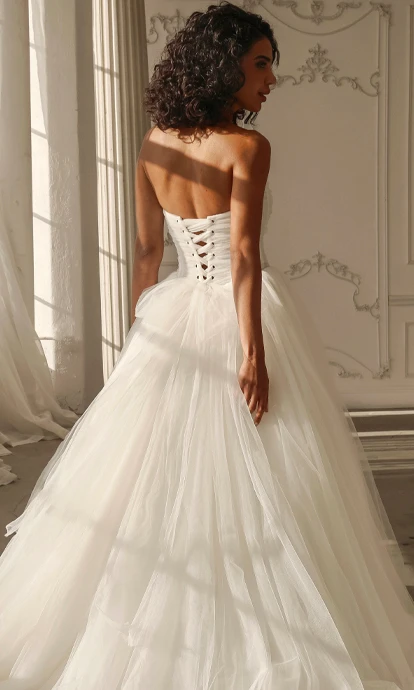 bride posing in tulle ballgown wedding dress with lace up back 