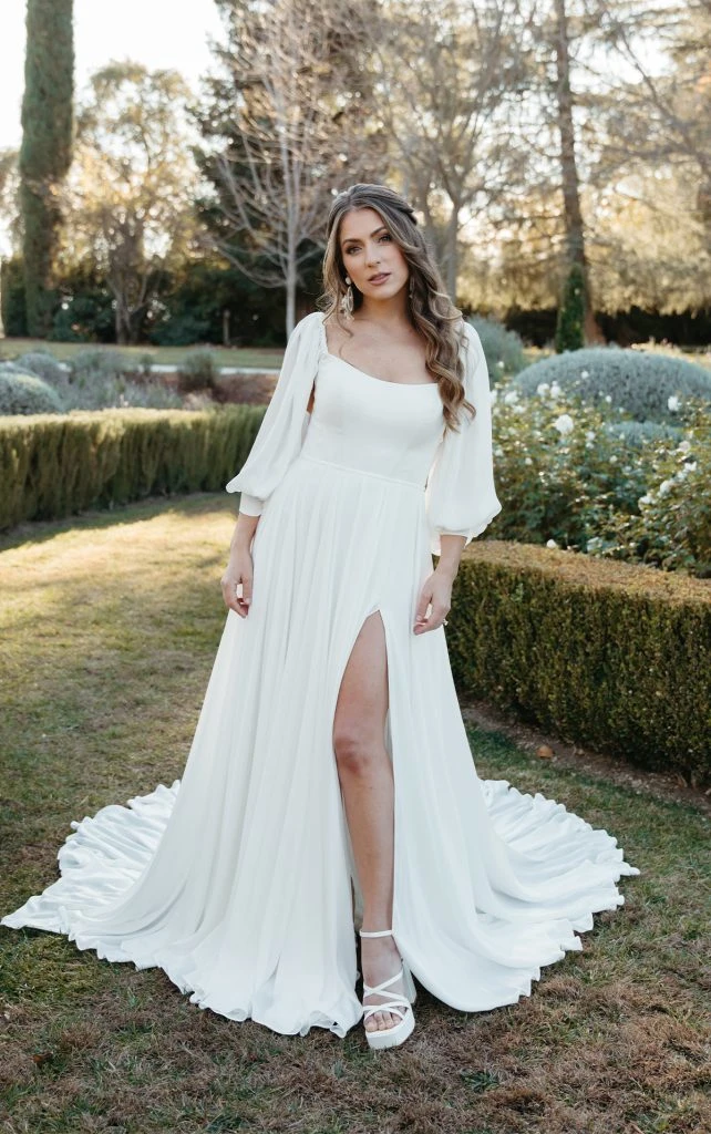 Bride wearing long sleeve bell sleeve wedding dress in a garden