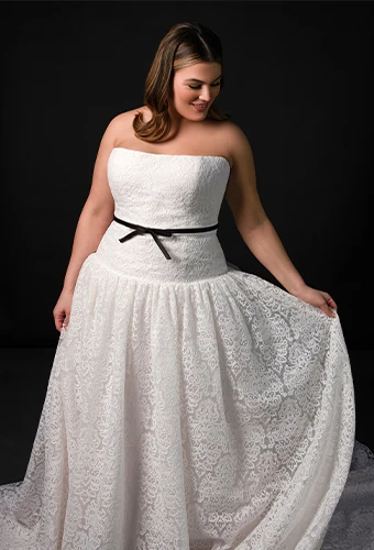 Bride wearing strapless plus size drop waist wedding dress with bow belt detail