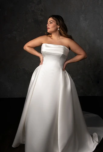 Bride wearing strapless plus size wedding dress with folded neckline and pleated skirt