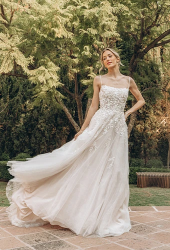 Bride wearing floral lace a-line wedding dress with spaghetti straps in garden