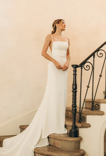 Bride wearing simple square neck column wedding dress with side cutouts and beaded straps