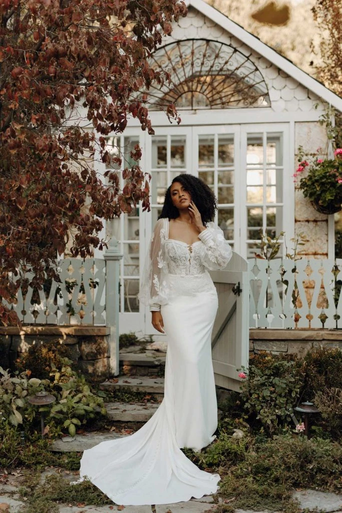 Bride wearing long-sleeve sheath wedding dress with lace details.
