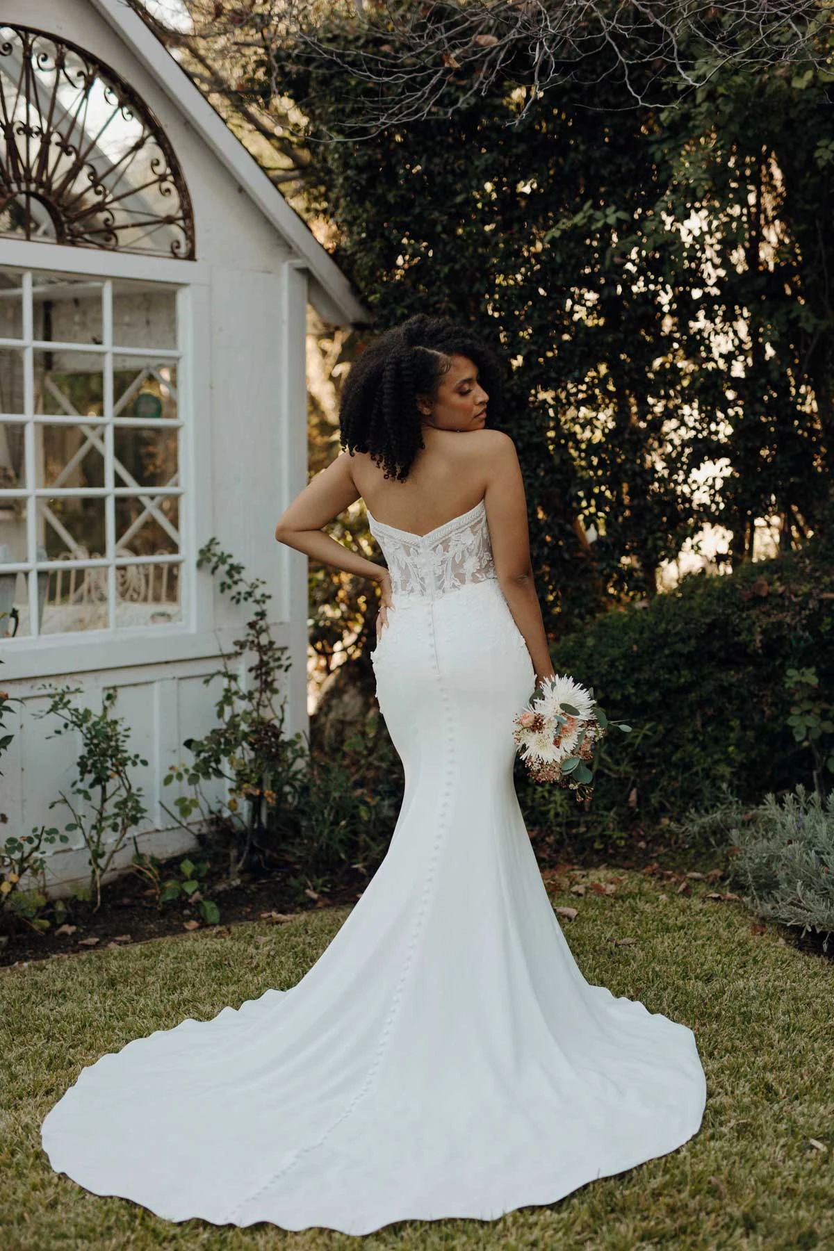 Bride wearing strapless sheath wedding dress with lace details. 
