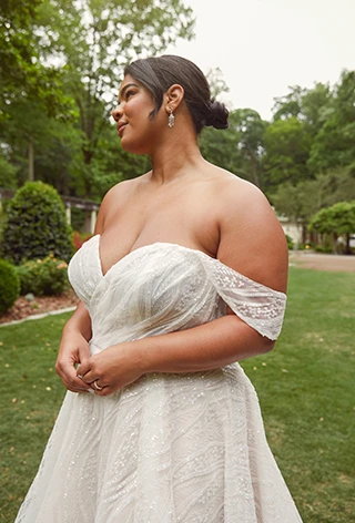 Plus-size bride wearing off-the-shoulder wedding dress with all-over lace.