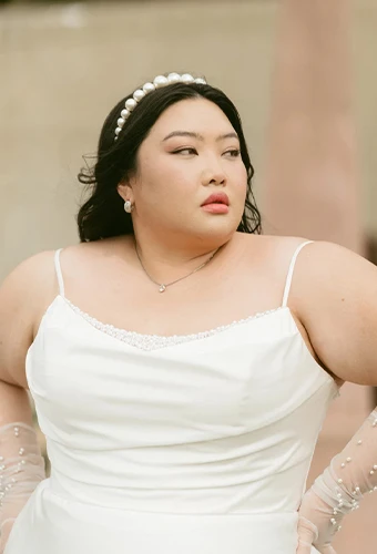 Plus size bride wearing simple wedding dress with scoop neckline and pearl details