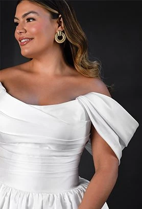 Plus size bride wearing wedding dress with off-the-shoulder straps and scoop neckline wearing bold earrings