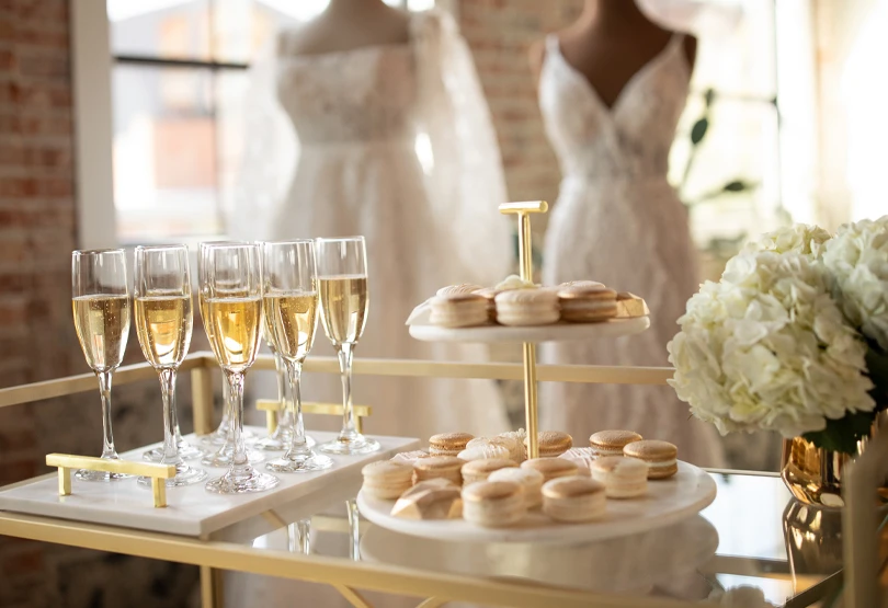 glass table of champagne and cookies at bridal salon