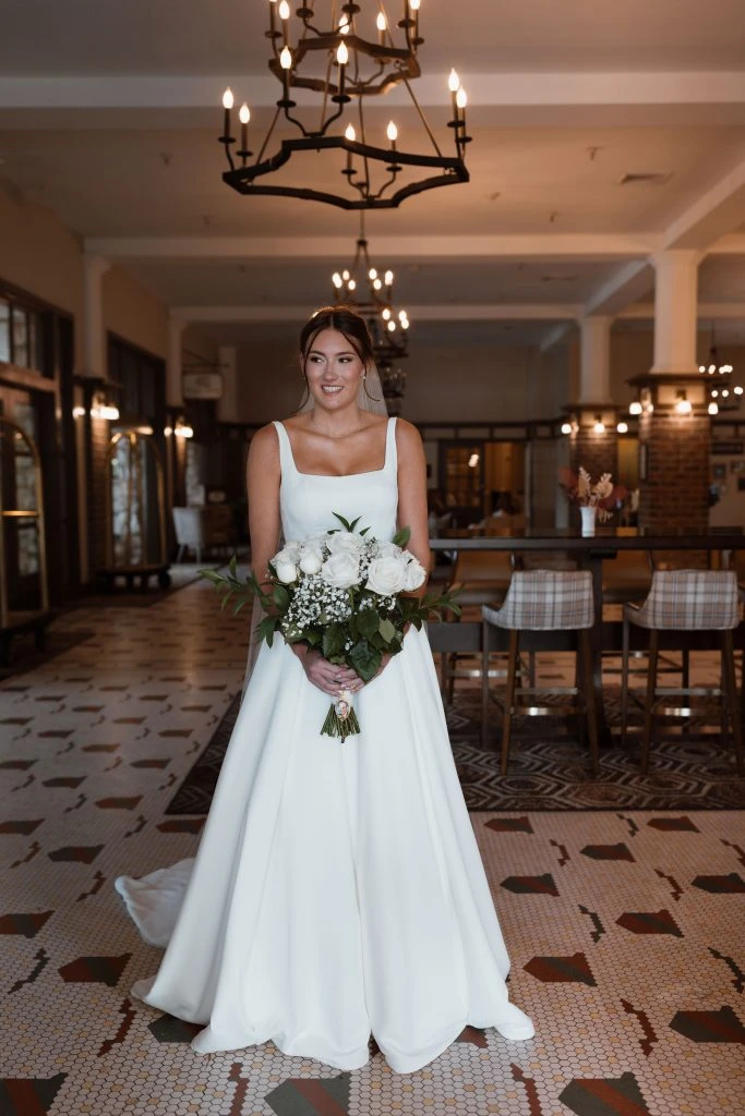 True Bride Genevieve poses in her wedding gown with a bouquet of flowers