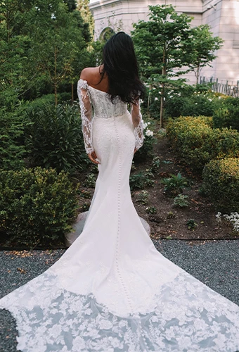 Bride wearing lace and satin wedding dress with long sleeves and fabric-covered buttons