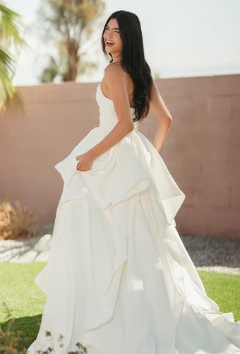 Bride wearing satin strapless ballgown wedding dress with layered skirt