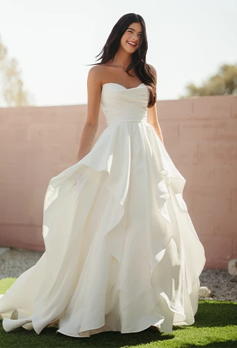 Bride wearing satin strapless ballgown wedding dress with layered skirt