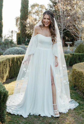 Bride wearing simple wedding dress with off-the-shoulder blouson sleeves and high leg slit
