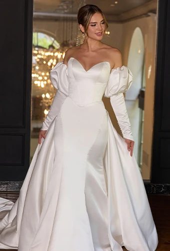 Bride wearing satin wedding dress with puff sleeves and overskirt