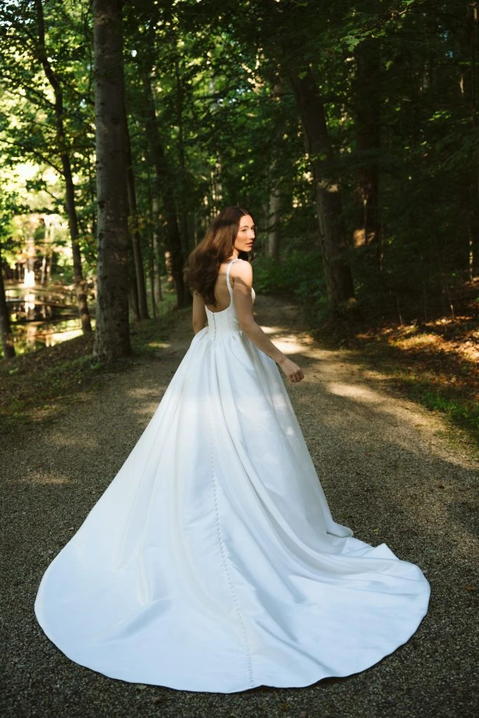 True bride showing off her wedding dress, posing in the forest