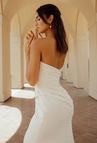 Bride wearing simple strapless wedding gown with fabric-covered buttons