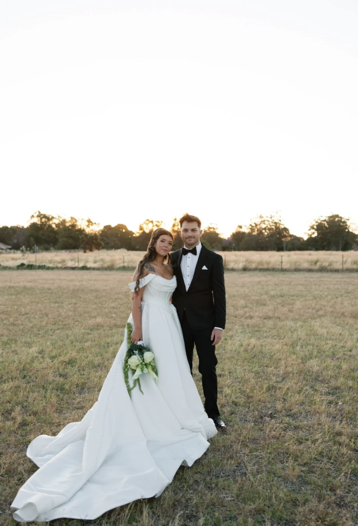 True bride Chloe posing with her husband in a field
