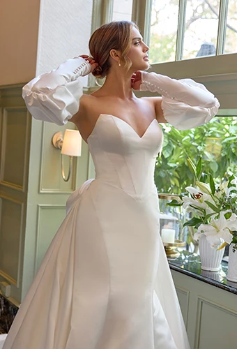 Bride wearing fit-and-flare wedding dress with over skirt and dramatic sleeves