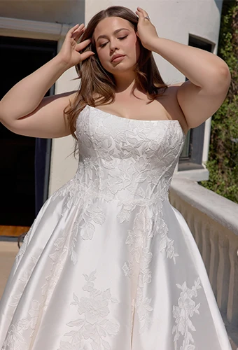 Plus size bride wearing strapless wedding dress with lace details and scoop neckline