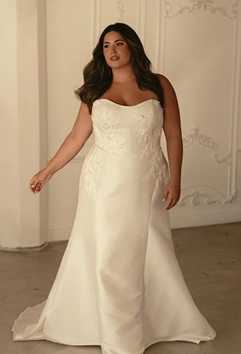 Plus size bride wearing fit-and-flare wedding dress with sweetheart neckline and lace details