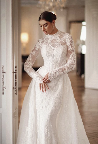 Bride wearing lace wedding dress with long sleeves and overskirt