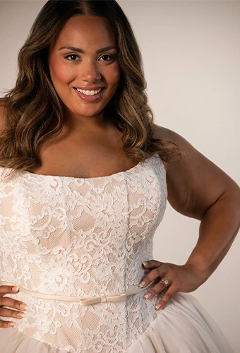 Plus size bride wearing lace wedding dress with scoop neckline and bow belt detail