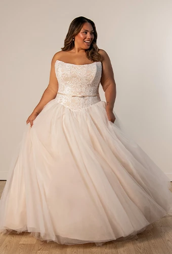 Plus size bride wearing ballgown wedding dress with lace bodice and bow belt detail