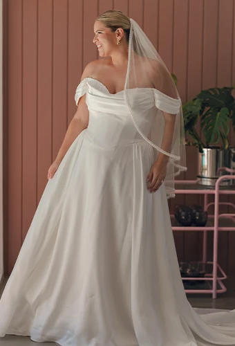 Plus size bride wearing satin a-line wedding dress with off the shoulder straps and sweetheart neckline