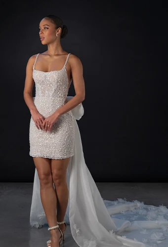 Bride wearing sparkling mini wedding dress with bow train detail