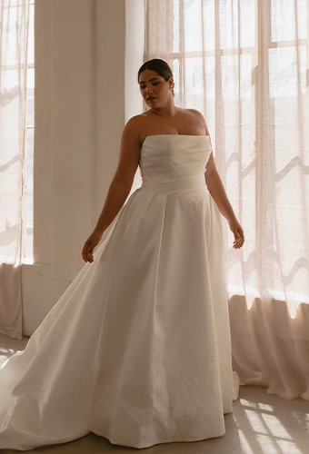 Plus size bride wearing simple strapless wedding dress with detachable overskirt